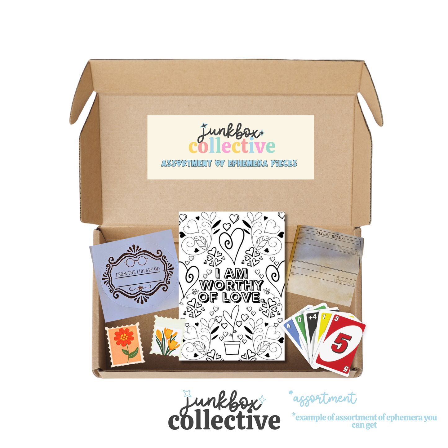 An open cardboard subscription box from Junkbox Collective labeled 'Assortment of Ephemera Pieces' on a white background, showing included items such as a black-and-white 'I Am Worthy of Love' card, a purple decorative card, small flower stamps, a colorful numbered card, and a stack of cards.