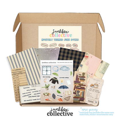 An open kraft cardboard box from Junkbox Collective filled with monthly themed sticker sets and paper accessories, shown on a white background with the brand name printed below.